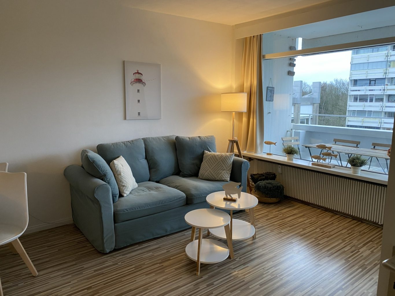 Gemütlicher Wohnbereich mit Schlafsofa Gemütlicher Wohnbereich mit Sofa und großen Fenstern in der Ferienwohnung Seeschwalbe