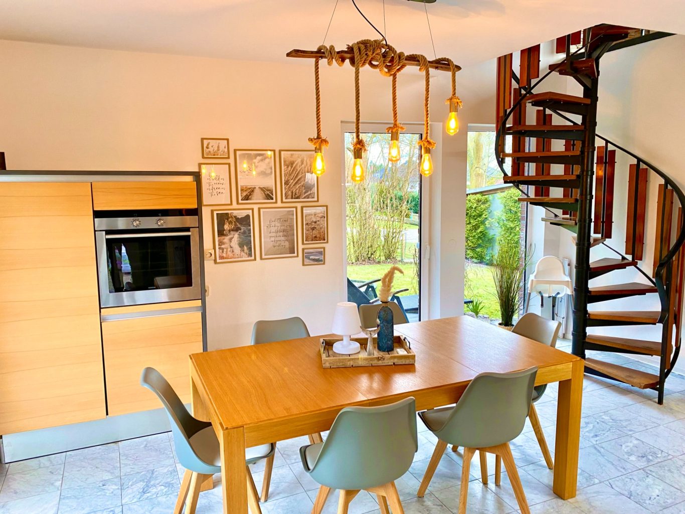 Offene Wohnküche mit Essbereich - perfekt für gemeinsame Abende in Sierksdorf Helles Esszimmer mit Holz-Tisch, modernen Stühlen und einer Wendeltreppe im Hintergrund in der Ferienwohnung Meeresbrise