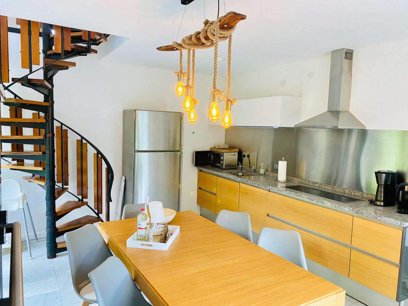 Voll ausgestattete Küche in der Ferienwohnung Meeresbrise Moderner Küchenbereich mit Esstisch, Wendeltreppe und großen Fenstern. Gemütliche Atmosphäre in der Ferienwohnung Meeresbrise